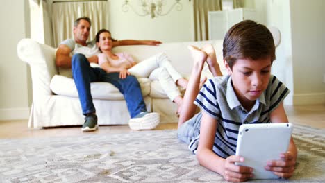 Boy-lying-on-rug-and-using-digital-tablet-in-living-room