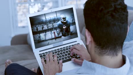Man-watching-american-football-match-on-laptop-in-living-room