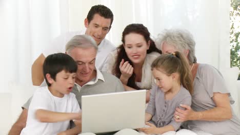 Parents,-gransparents-and-children-sitting-on-sofa-using-a-laptop