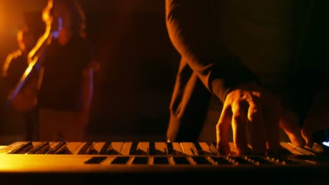 Mid-section-of-musician-playing-electronic-piano-in-studio