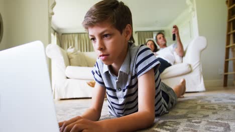 Junge-Liegt-Auf-Teppich-Und-Benutzt-Laptop-Im-Wohnzimmer