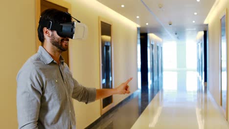 Male-executive-using-virtual-reality-headset-in-corridor