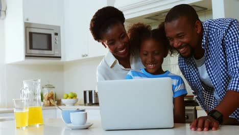 Parents-and-daughter-using-laptop-in-kitchen