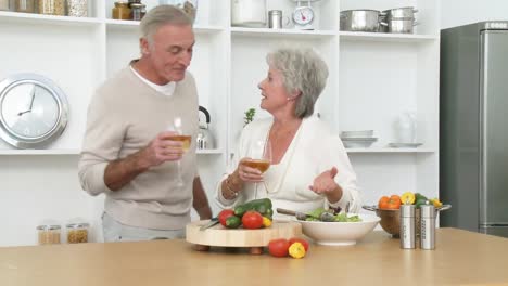 Smiling-senior-couple-preparing-a-salad-in-the-kitchen