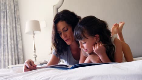 Mutter-Und-Tochter-Lesen-Ein-Buch,-Während-Sie-Im-Schlafzimmer-Auf-Dem-Bett-Liegen