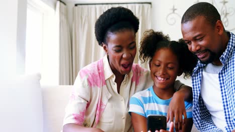 Parents-and-daughter-mobile-phone-in-living-room