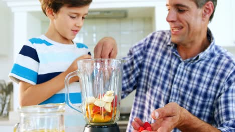 Father-and-son-preparing-smoothie-in-kitchen