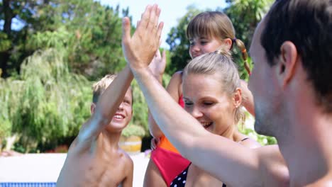 Happy-family-giving-high-five-to-each-other-near-pool-side