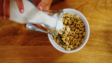 Hands-of-kid-pouring-milk-into-cereal-bowl