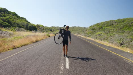 Hombre-Triatleta-Llevando-Bicicleta-En-La-Carretera-Rural.