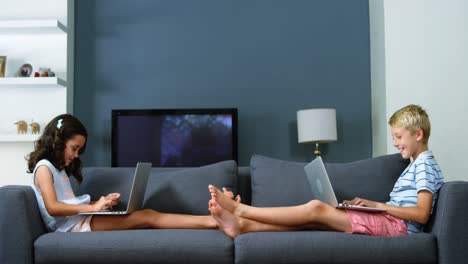 Siblings-using-laptop-in-living-room
