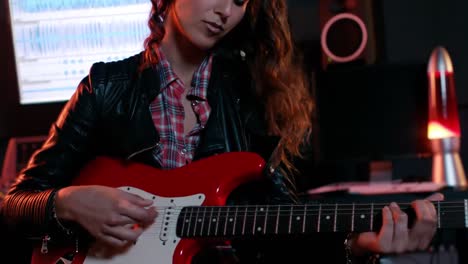Woman-playing-electric-guitar-in-recording-studio