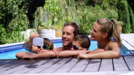 Happy-family-using-mobile-phone-near-poolside