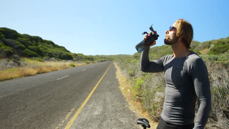 Triathlete-man-drinking-water-in-the-countryside-road