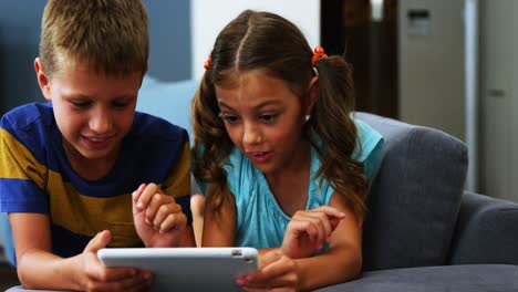 Siblings-using-digital-tablet-in-living-room