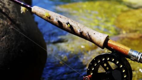 Fly-fishing-rod,-reel-and-hook-on-rock