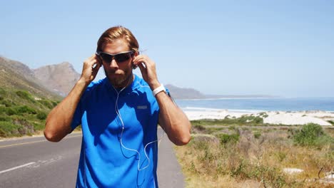 Triathlete-man-wearing-earbuds-in-the-countryside-road