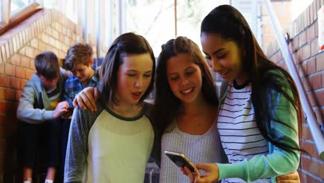 Smiling-schoolgirls-taking-selfie-with-mobile-phone-in-corridor