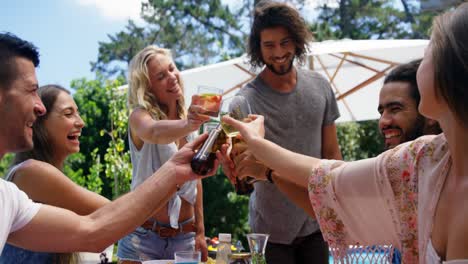 Group-of-happy-friends-toasting-glasses-of-drinks-at-outdoors-barbecue-party