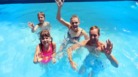 Portrait-of-happy-family-waving-hand-in-swimming-pool