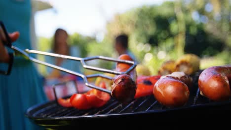 Girl-flipping-sausages-on-barbecue