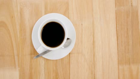 Black-coffee-served-in-white-cup-on-wooden-plank