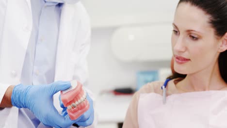 Dentist-showing-model-teeth-to-patient