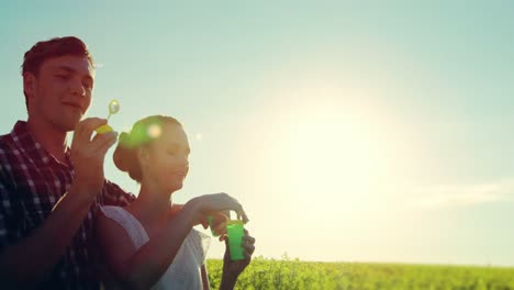 Romantic-couple-blowing-bubbles-in-mustard-field