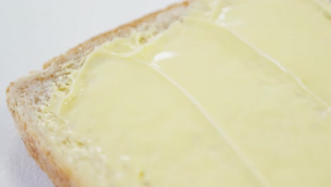 Butter-spread-on-bread-slice-against-white-background