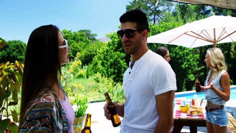 Couple-interacting-while-having-a-bottle-of-beer-near-poolside