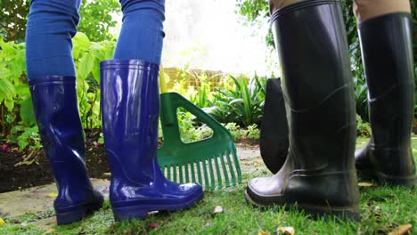 Couple-standing-with-gardening-equipment-in-garden