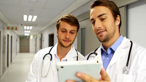 Doctors-discussing-over-digital-tablet-in-corridor