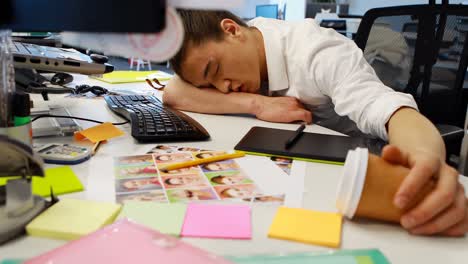 Male-graphic-designer-sleeping-at-desk