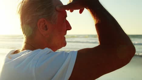 Senior-man-shielding-eyes-on-beach