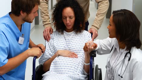 Doctors-and-man-comforting-pregnant-woman-in-corridor