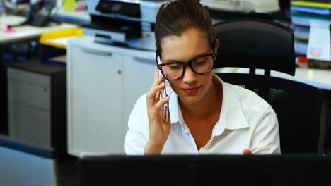 Female-executive-talking-on-mobile-phone-at-desk
