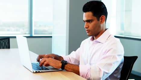 Male-executive-working-on-laptop-at-desk