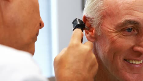 Médico-Examinando-El-Oído-Del-Paciente-Con-Otoscopio