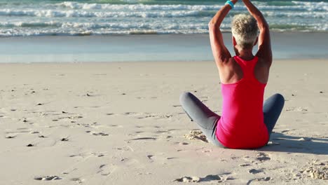 Ältere-Frau-Macht-Yoga-Am-Strand