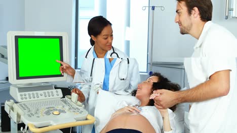 Doctor-showing-sonography-report-to-pregnant-woman-on-monitor