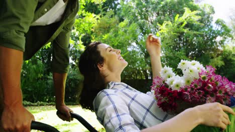 Man-kissing-woman-in-wheelbarrow-in-garden