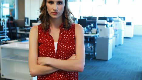 Female-executive-standing-with-arms-crossed-in-office