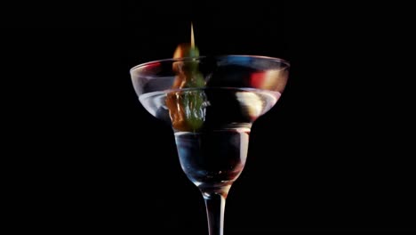Olive-stick-falling-in-cocktail-glass