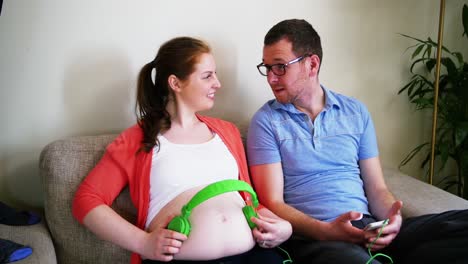 Schwangere-Frau-Platziert-Kopfhörer,-Während-Sie-Mit-Einem-Mann-Interagiert