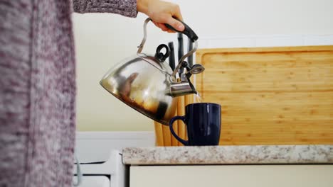 Mid-section-of-woman-preparing-coffee-in-kitchen