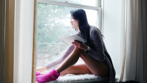 Woman-using-digital-tablet-while-having-coffee-in-bedroom