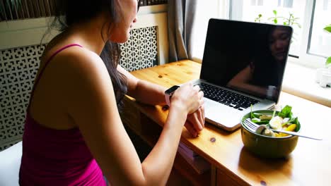 Woman-sitting-at-table-and-using-smart-watch