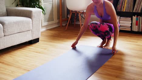 Beautiful-woman-unrolling-exercise-mat-on-wooden-floor