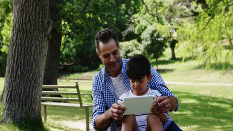 Boy-sitting-on-his-fathers-lap-and-using-digital-tablet