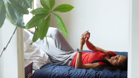 Woman-using-mobile-phone-in-bedroom